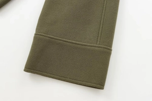 Gros plan détaillé du poignet d'un manteau en feutre vert armée montrant les coutures
