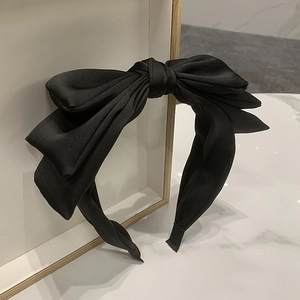 Close-up of a layered black satin bow headband with premium silk texture details