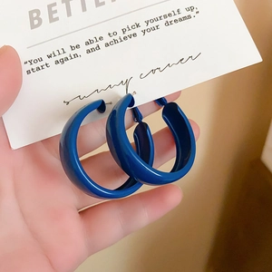 Close-up of vibrant Klein blue thick hoop earrings with polished glossy finish