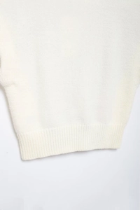 Close-up of white knitted sweater hem showing detailed ribbing and soft texture