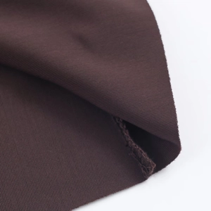 Macro detail of dark brown ribbed velvet fabric with high-density knit and neat overlock stitching