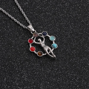 Macro detail of silver chakra pendant with seven colorful gemstones on a black background