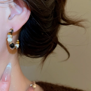 Close-up of model wearing C-shaped tiger eye stone beaded earrings with silver accents