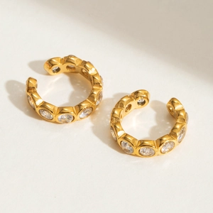 Detailed view of gold-plated ear cuffs with shimmering white zircon stones set in steel
