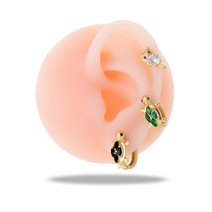 Gold owl and turtle ear cuffs set with colorful zircon on a model ear display
