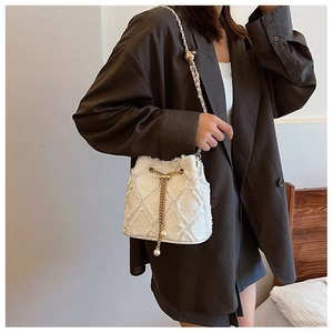 Chic cream white tweed bucket bag with metal chain strap and pearl charm on a model