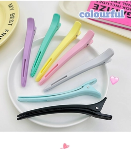Macro detail of seven colorful matte large hair clips arranged in a fan shape on a tray