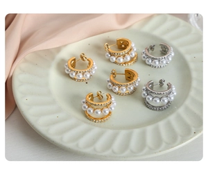 Détail de boucles d'oreilles en C dorées et argentées avec perles et cristaux sur un plateau