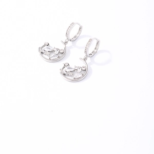 Gros plan sur les boucles d'oreilles lune en argent avec motif oiseau et zircons