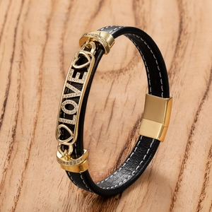 Gros plan bracelet en cuir noir avec breloque LOVE dorée et fermoir magnétique