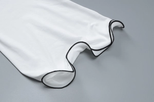 Détail du tissu en maille blanche avec coutures contrastées noires et bordure ondulée