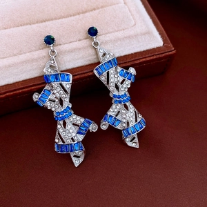 Macro shot of bow earrings with blue rectangular zircons and white crystals