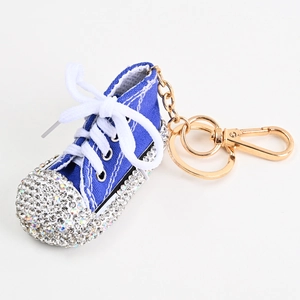 Detail eines blauen Segeltuch-Schuh-Schlüsselanhängers mit glitzernden Strasssteinen und Goldkette
