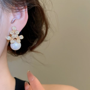 Detail of elegant pearl drop earring featuring zircon-encrusted gold floral design