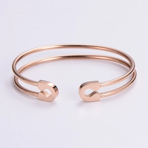 Detail of rose gold minimalist open bangle featuring a unique safety pin head design