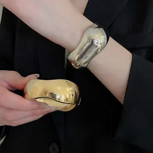 Polished metallic oval open cuff bracelet in gold and silver finish on model