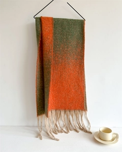 Close-up of green and orange gradient scarf texture with elegant beige tassels
