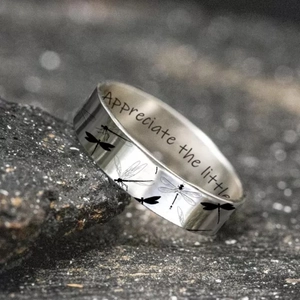 Silver dragonfly ring with 'Appreciate the little things' engraving on a dark rock