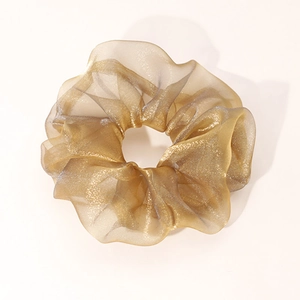 Close-up of champagne gold organza scrunchie showing glossy fabric texture and pleats