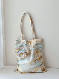 Close-up of artistic marble grain canvas tote bag hanging against a clean white wall