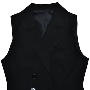 Détail du gilet noir à double boutonnage avec revers en pointe et texture de tissu lisse