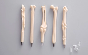 Top view of five unique bone-shaped ballpoint pens with caps on a clean grey background