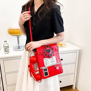 Detailed view of red retro telephone crossbody bag featuring circular dial and handset