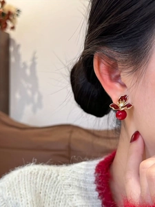 Gros plan sur des boucles d'oreilles fleur vintage en émail rouge et métal doré