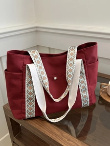 Dettaglio della borsa tote in nylon rosso con tracolla in tessuto a motivi geometrici