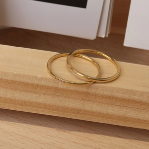 Details von zwei minimalistischen Gold-Titanringen mit Zirkonia auf einem Holzdisplay