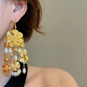 Detail von Vintage-Goldblumenohrringen mit eleganten Perlenquasten an einem Model