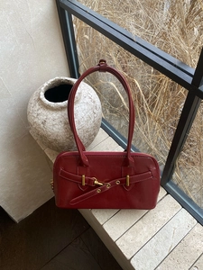 Detail of red leather bowling bag with gold hardware and decorative buckle straps