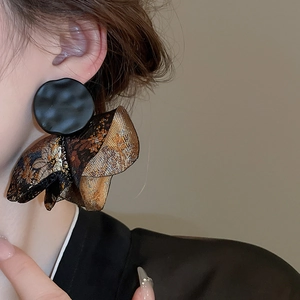 Close-up of vintage flower patterned jacquard and hammered metal disc earrings
