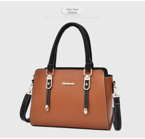 Detail view of lychee grain leather texture with gold logo on two-tone crossbody bag