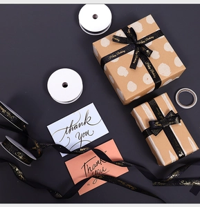 Detail of black gold-stamped Happy Birthday ribbon with kraft gift box and thank you card