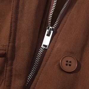 Detailed close-up of dark brown twill fabric with high-quality metal zipper and button