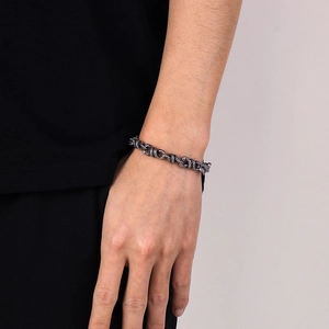 Detailed view of punk double snake wrap bracelet in vintage steel on male model wrist