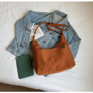 Flat lay of caramel brown large capacity nylon hobo bag with adjustable strap and fashion tag
