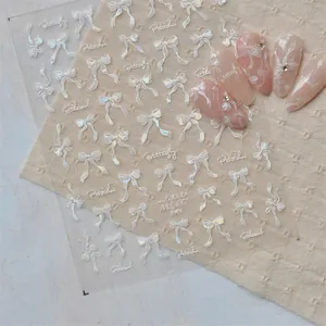 Detail of shell luster nail art stickers featuring black and white bows and typography