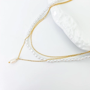 Detail of layered gold necklace featuring elegant white pearls and a baroque pearl pendant