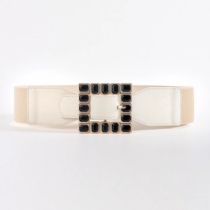 Detail of beige elastic waist belt with gold square buckle and black gemstones