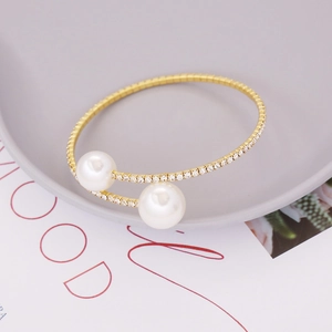 Elegant gold double pearl bracelet with rhinestone pavé band on a minimalist display