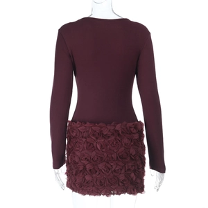 Détail de l'applique de rose 3D sur l'ourlet d'une robe bordeaux à manches longues