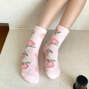 Gros plan de chaussettes roses en polaire corail avec motifs de pêches et texture douce