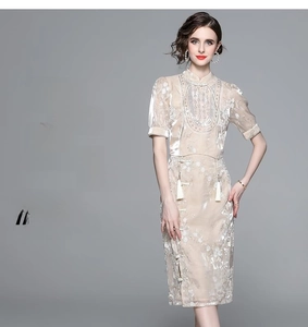 Detailed view of silver floral embroidery and fringed hem on a beige satin dress