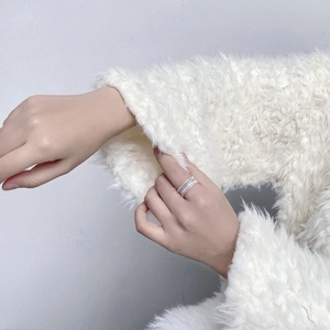 Detailed close-up of a silver multi-layered woven ring with sparkling cubic zirconia on a hand