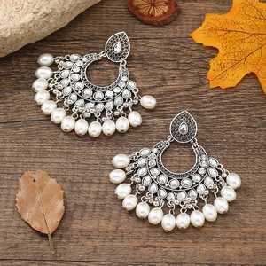 Bohemian silver fan earrings with pearls and dark rhinestones on wood surface