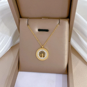 Close-up of gold Tree of Life pendant with crystals in a beige jewelry box