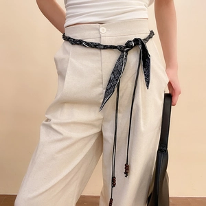 Détail d'une ceinture en soie avec motif paisley et perles en bois sur un pantalon