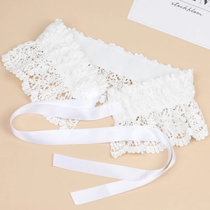 Close-up of intricate white lace waist belt with delicate floral patterns and satin ribbons